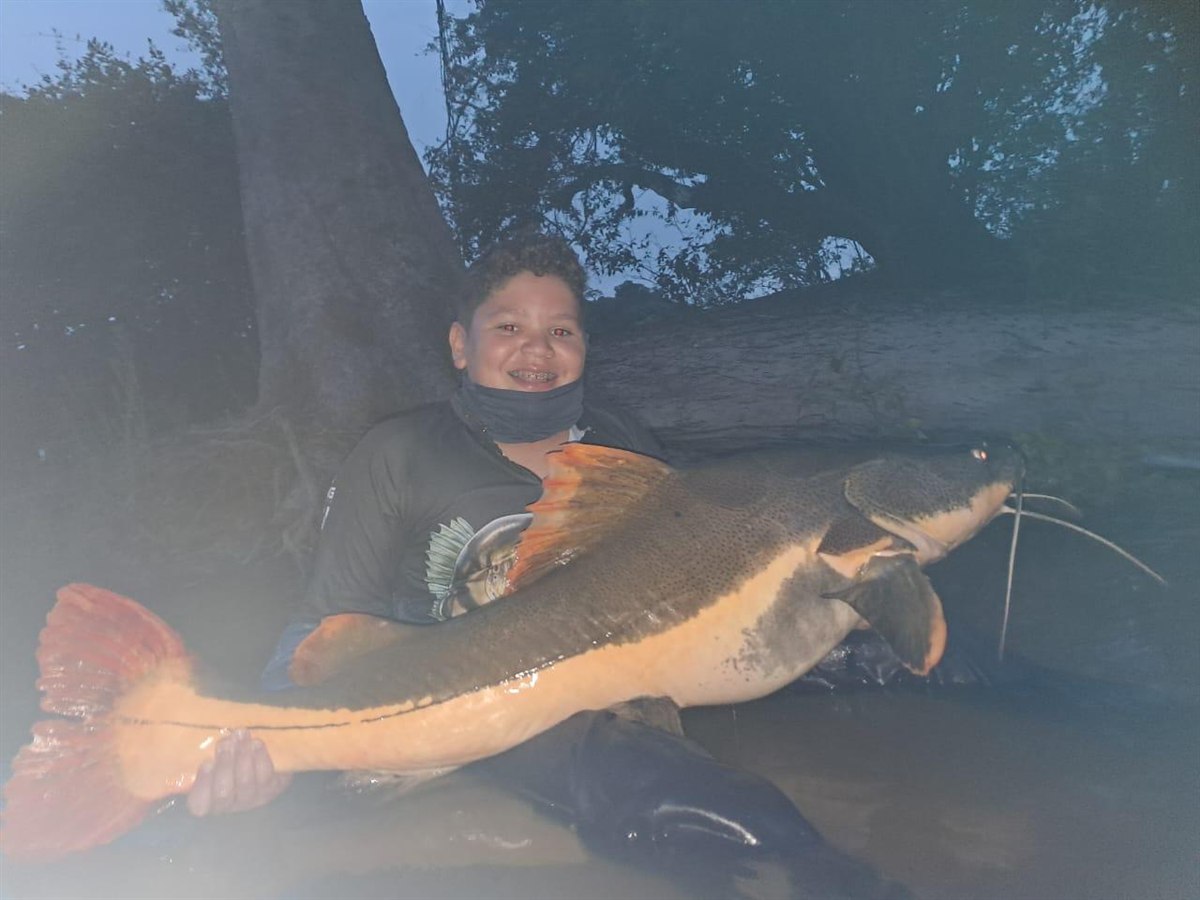Jovem pescador com uma grande pirarara