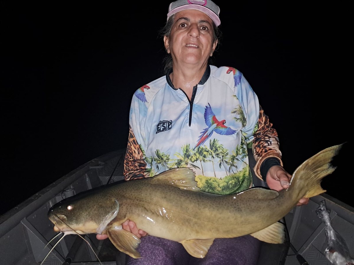Pescadora com peixe de couro durante pescaria noturna