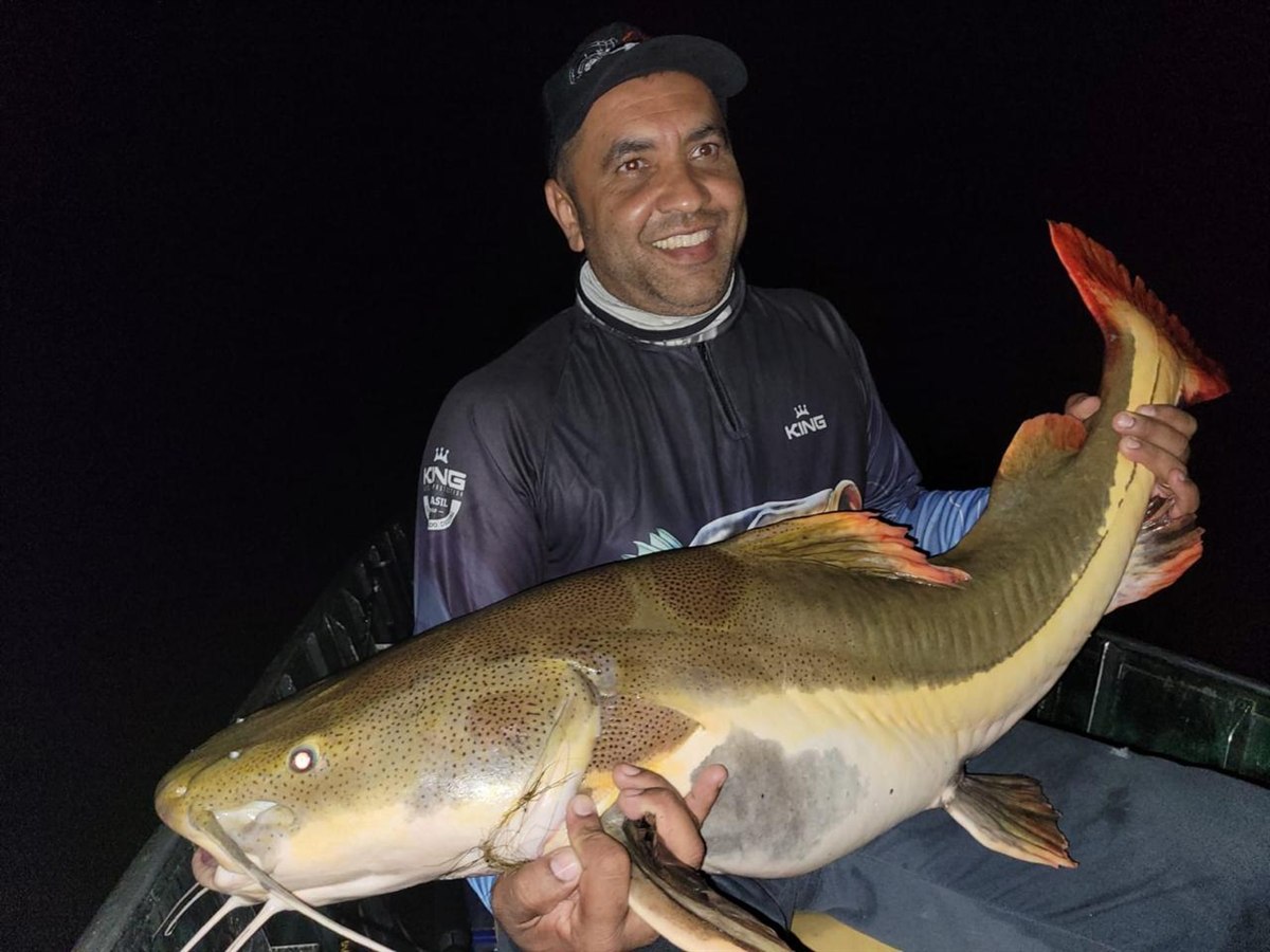 Pescador e uma pirarara capturada à noite