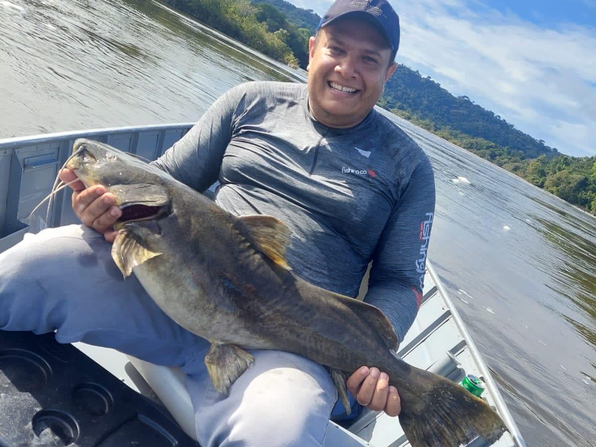 Pescador com peixe de couro em dia de águas abertas