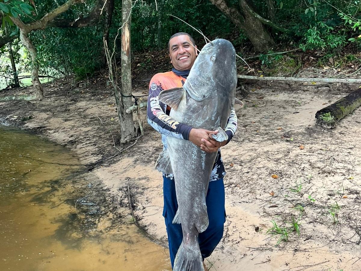 Pescador com peixe capturado junto à mata preservada